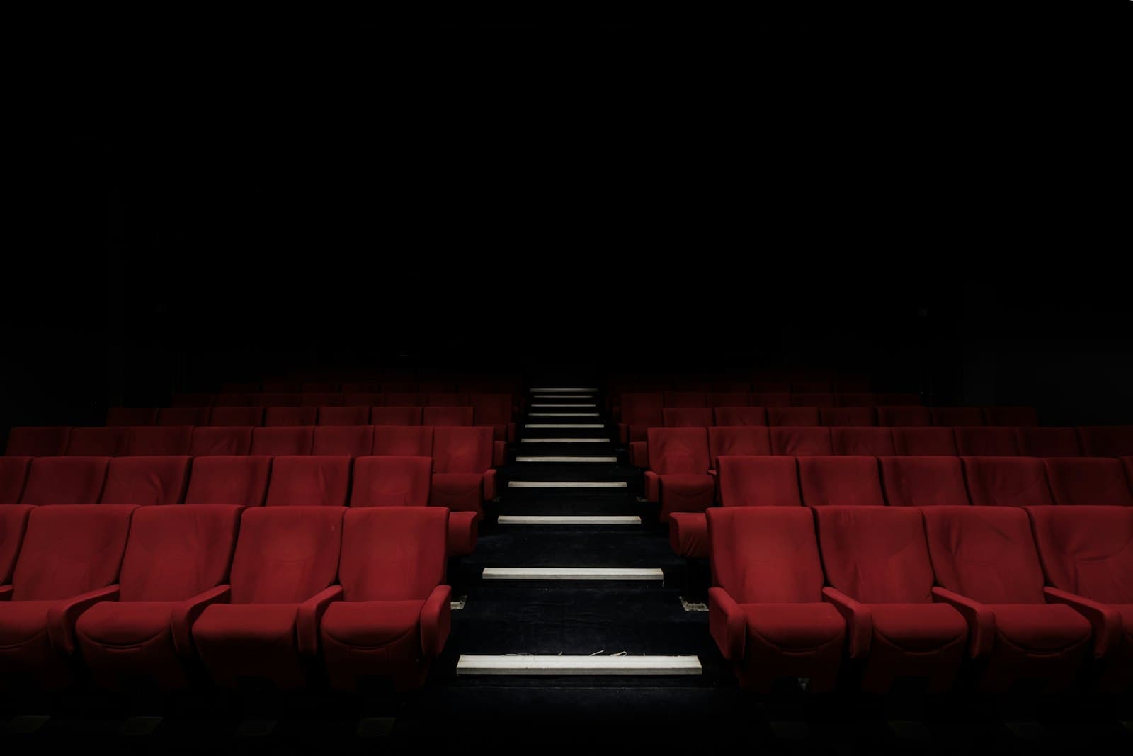 Rows of red cinema seats in a dark auditorium