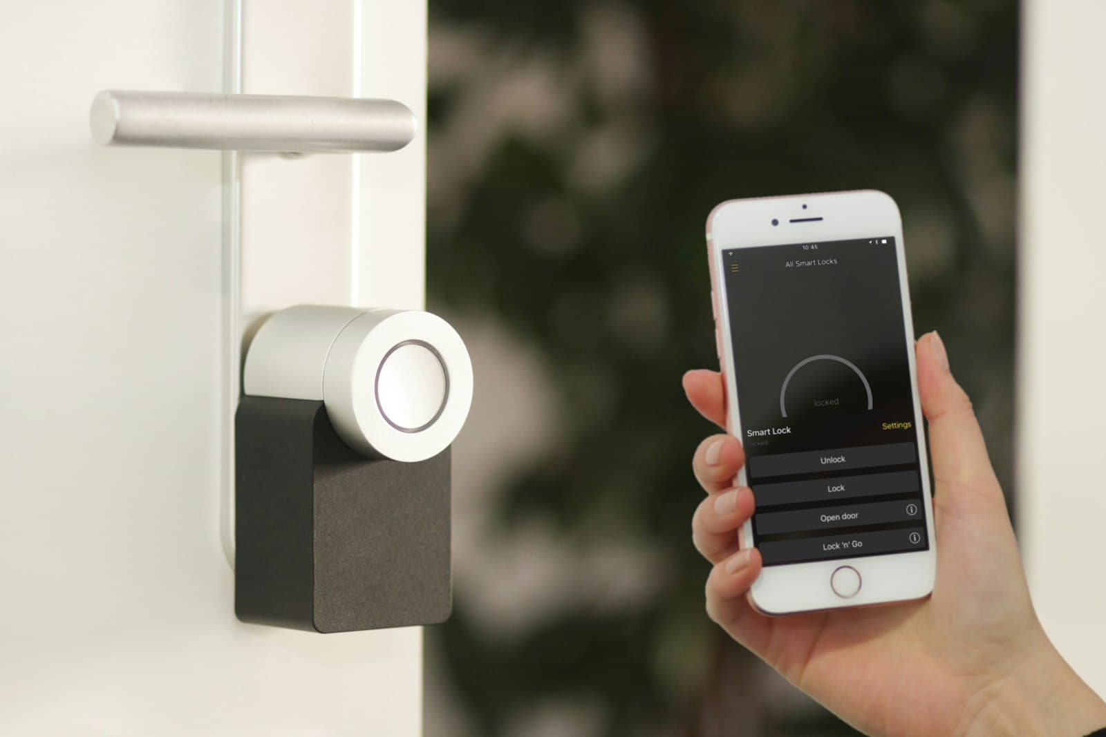 A hand holding a phone beside a lock on a white door